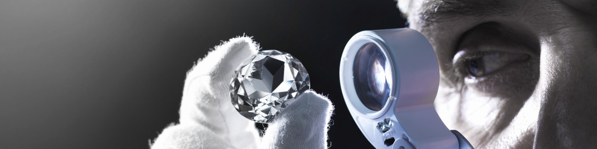Un hombre examina los diamantes con una lupa.